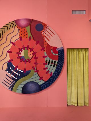 colorful round rug on a pink wall