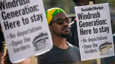 Demonstrators hold placards during a protest in support of the Windrush generation in Windrush Square, Brixton 
