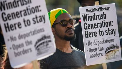 Demonstrators hold placards during a protest in support of the Windrush generation in Windrush Square, Brixton 