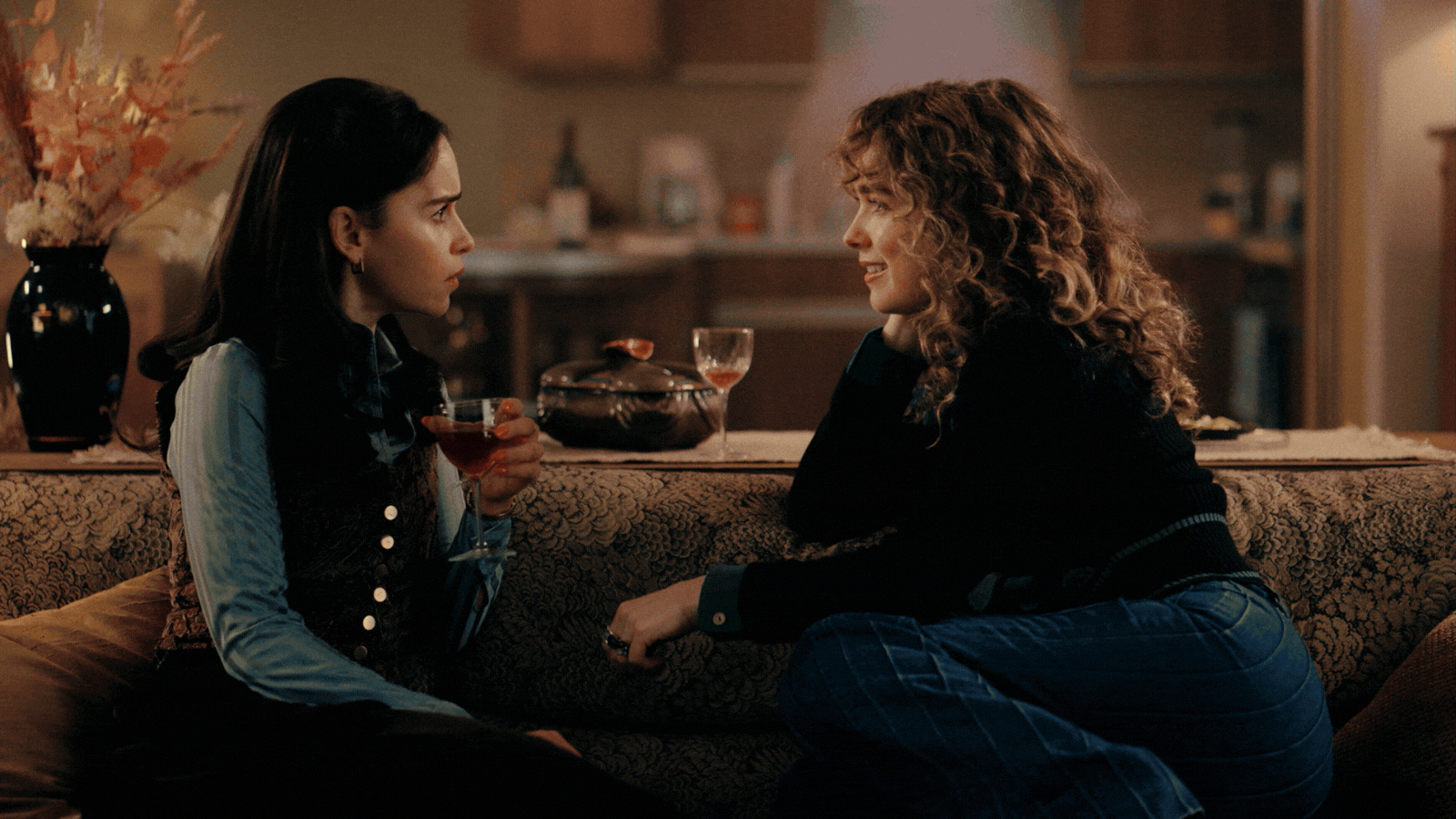 A rotating gif spotlighting a series of film sets, including warmly lit living rooms with people chatting in them, an empty, 1970s-style office in teal and red brick, a Christmas party, and a colorful, stained-glass-decorated hallway.