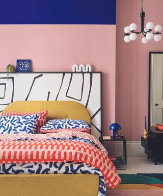 bedroom with pink walls, colourful bedding, and blue ceiling
