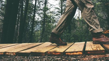 Best walking shoes for men: Person walking across a wooden bridge