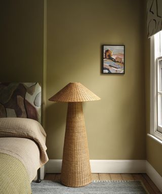 modern bedroom with gold walls, a rattan floor lamp and patterned headboard