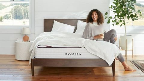 Woman sitting on an Awara Natural Hybrid mattress in a bedroom