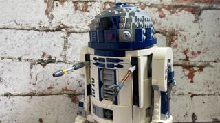 Lego R2-D2 against a brick wall, with tools out