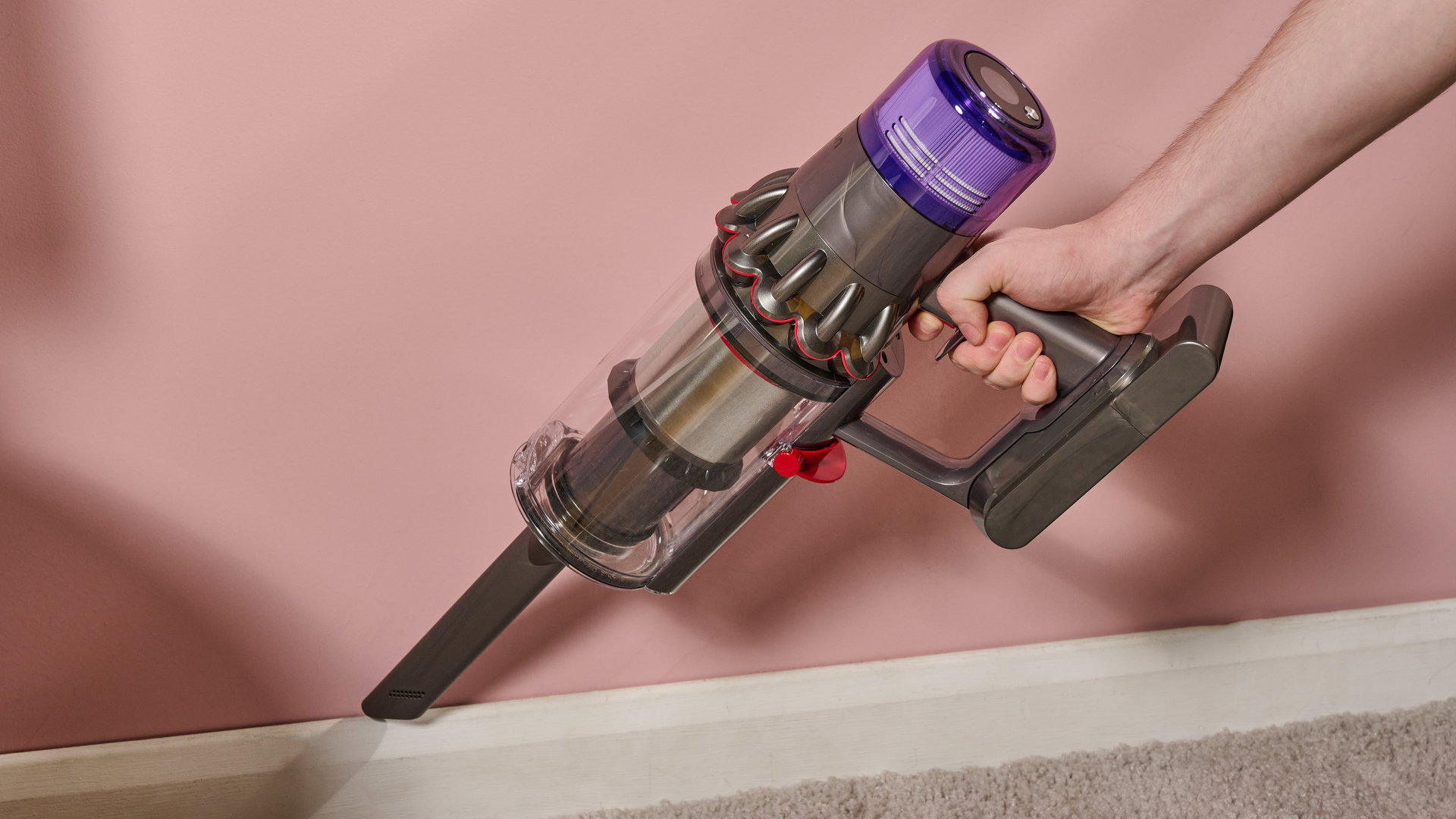Dyson V11 stick vacuum in handheld mode, with Crevice attachment, cleaning a baseboard