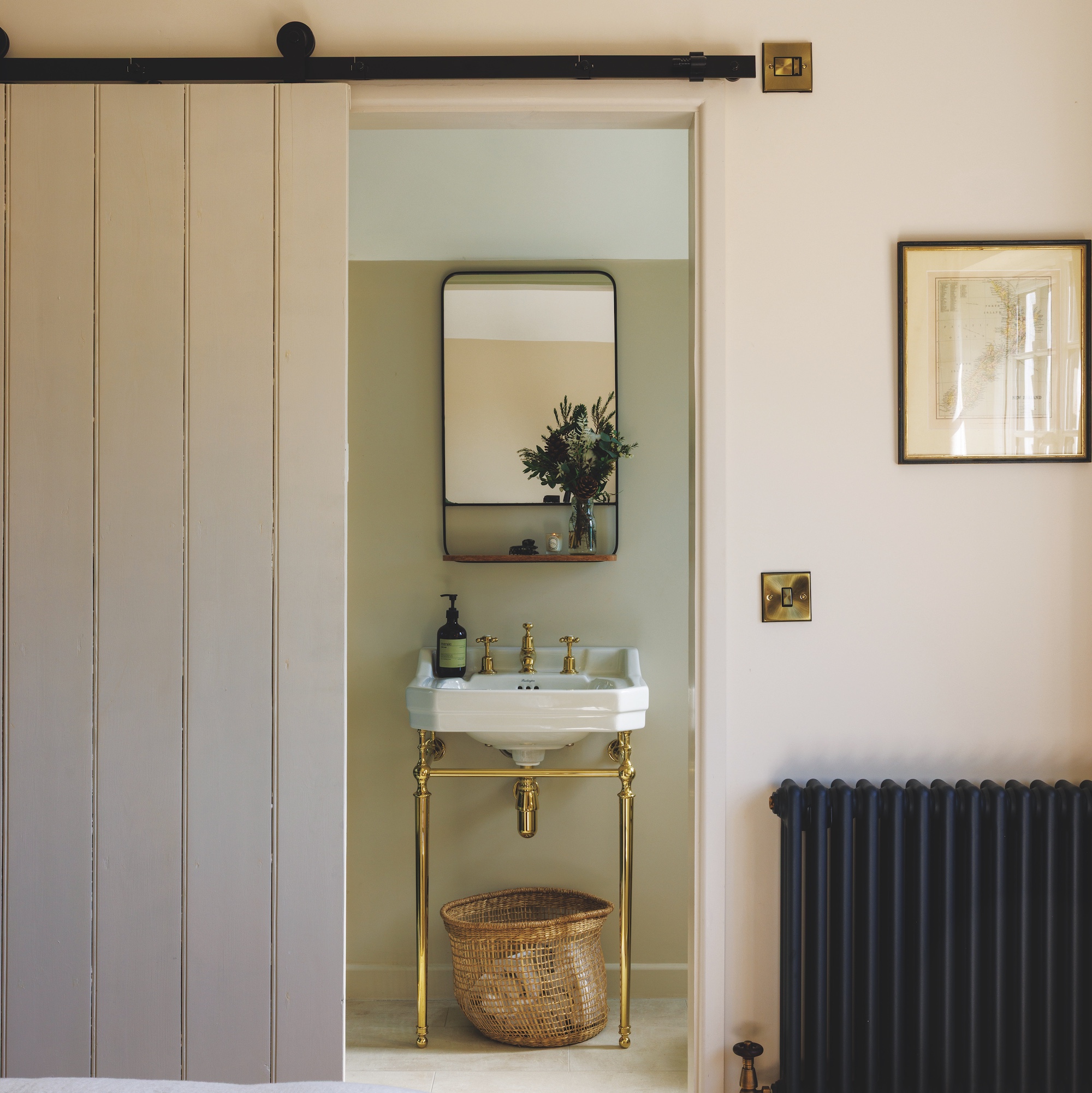 brass washstand with white basin in ensuite bathroom with barn style sliding door