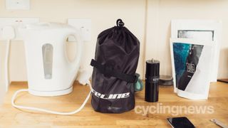 A bike cover stuffed into a sack next to a kettle