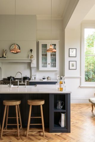 Blue and white shaker kitchen, an island with sink and glass fronted cabinetry by deVOL