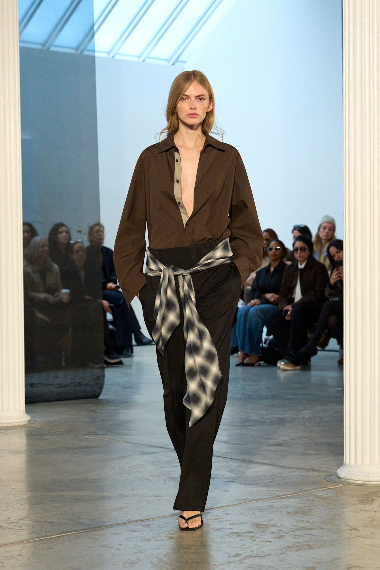 A look from Kallmeyer's's F/W 25 runway show including a brown shirt tucked into black pants with a gray plaid belt.