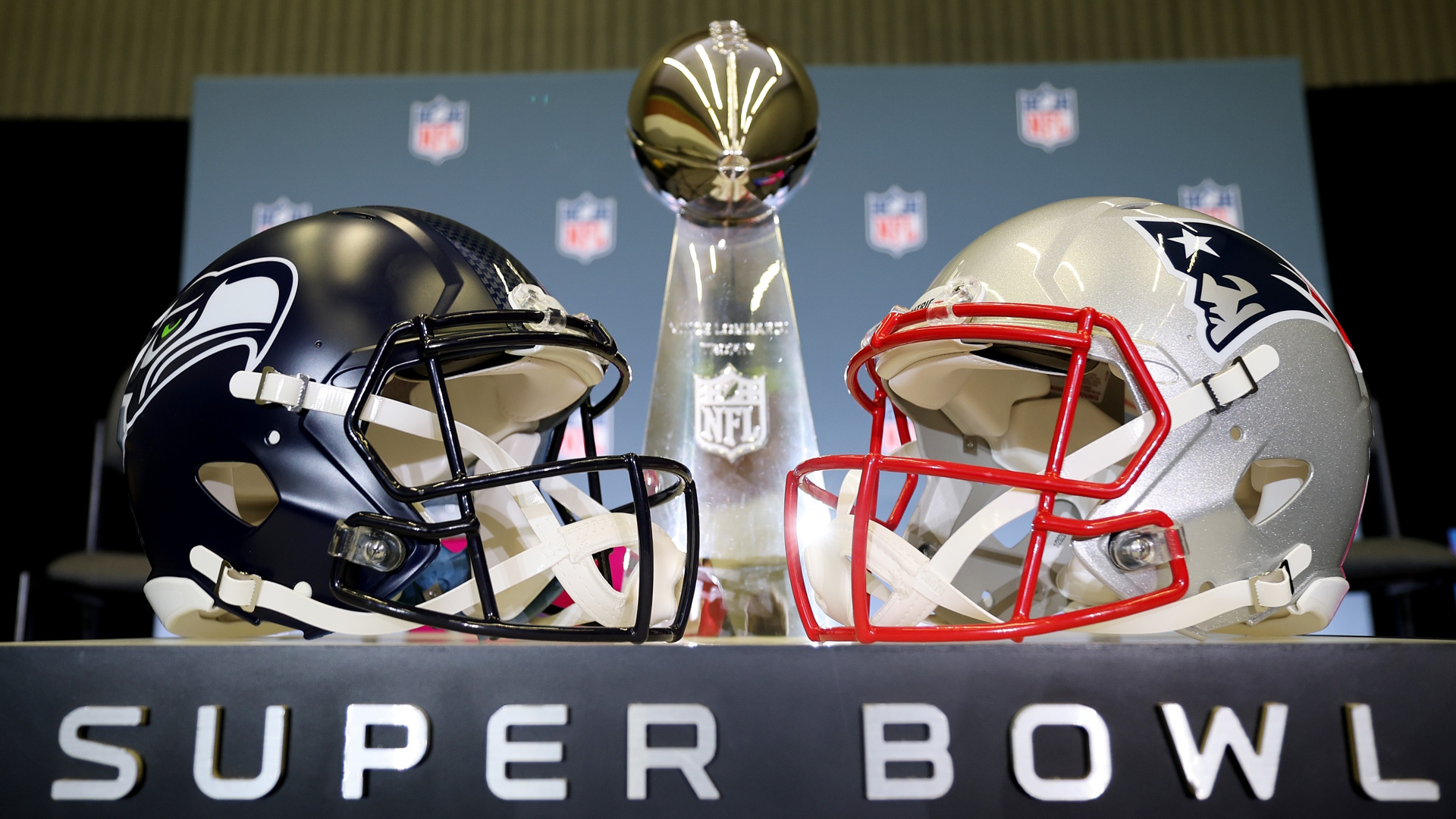 The Vince Lombardi Trophy is framed by the Seattle Seahawks and New England Patriots helmets during Super Bowl LX Opening Night.
