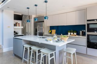 modern grey kitchen with blue pendant lights and white bar stools