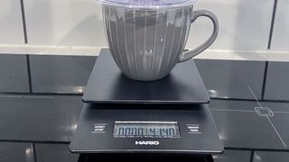 a black coffee scale by Hario is photographed in real-life usage in a kitchen