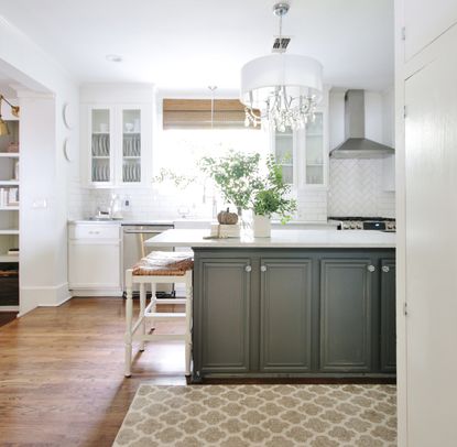A neutral kitchen with a patterned geometric rug and an island with light grey cabinets