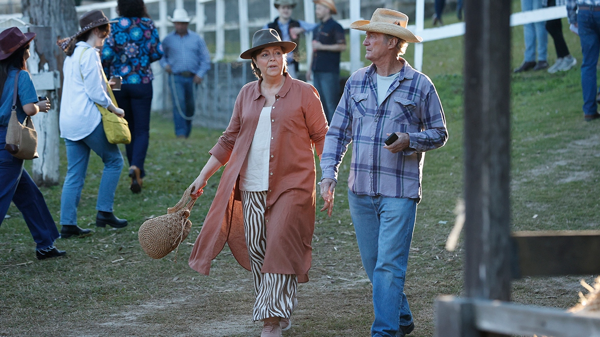 Darby and Joan walking through an outdoor event with cowboy hats on.