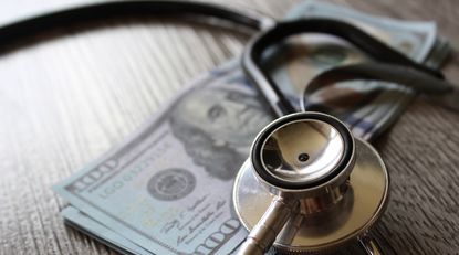Stethoscope and money on a wooden table.