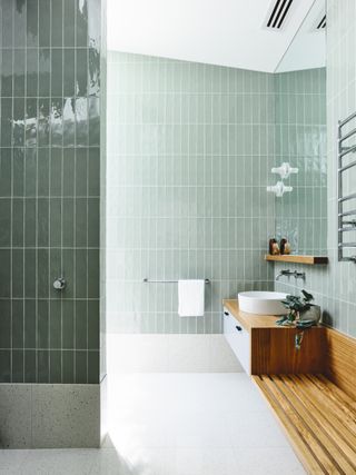 A bathroom with light and dark green wall tiles