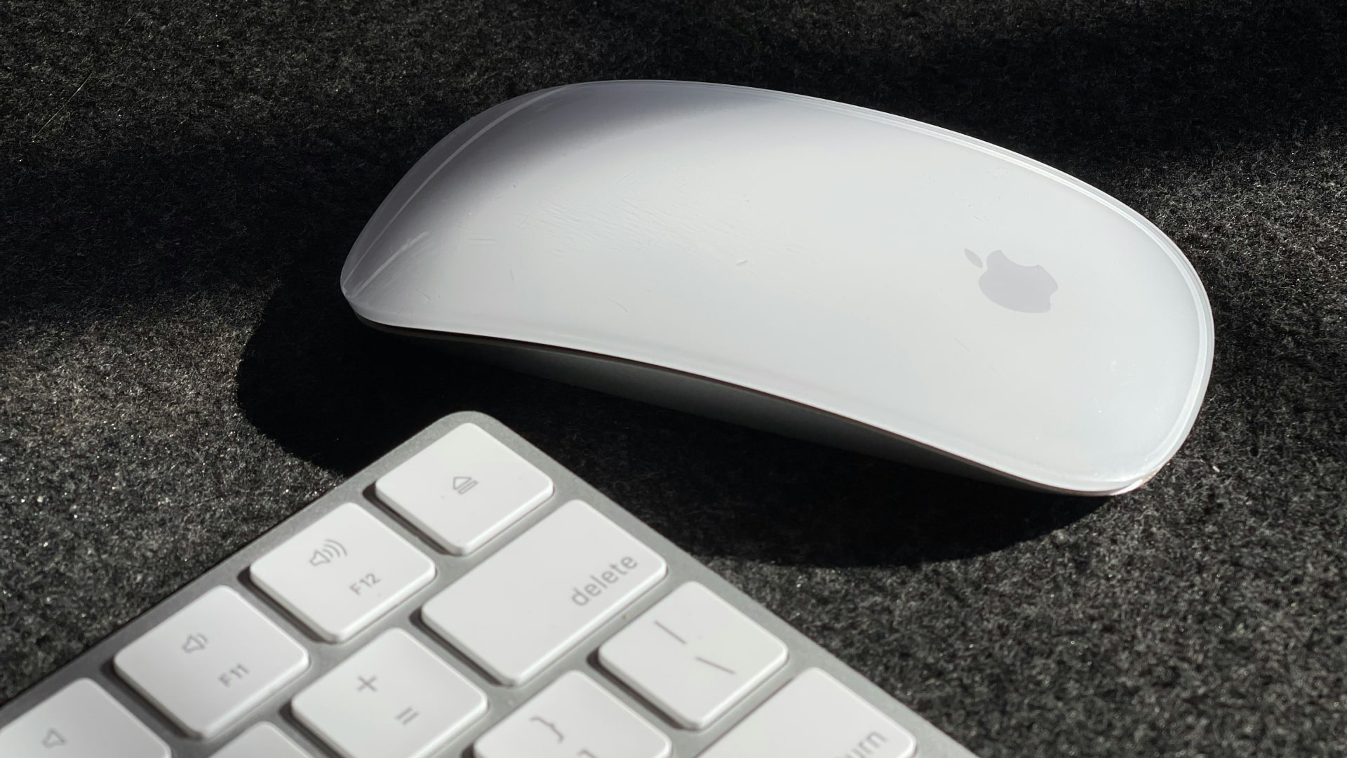 Une Magic Mouse sur un bureau à côté d'un Magic Keyboard.