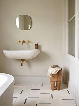 A bathroom with beige plaster on the walls and decorative floor tiles