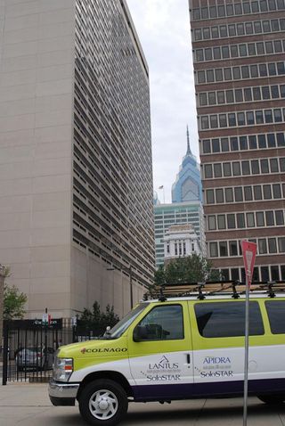 The Team Type 1 bus is dwarfed by the Philadelphia skyline.