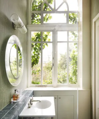 A bathroom window and vanity unit with a circular mirror