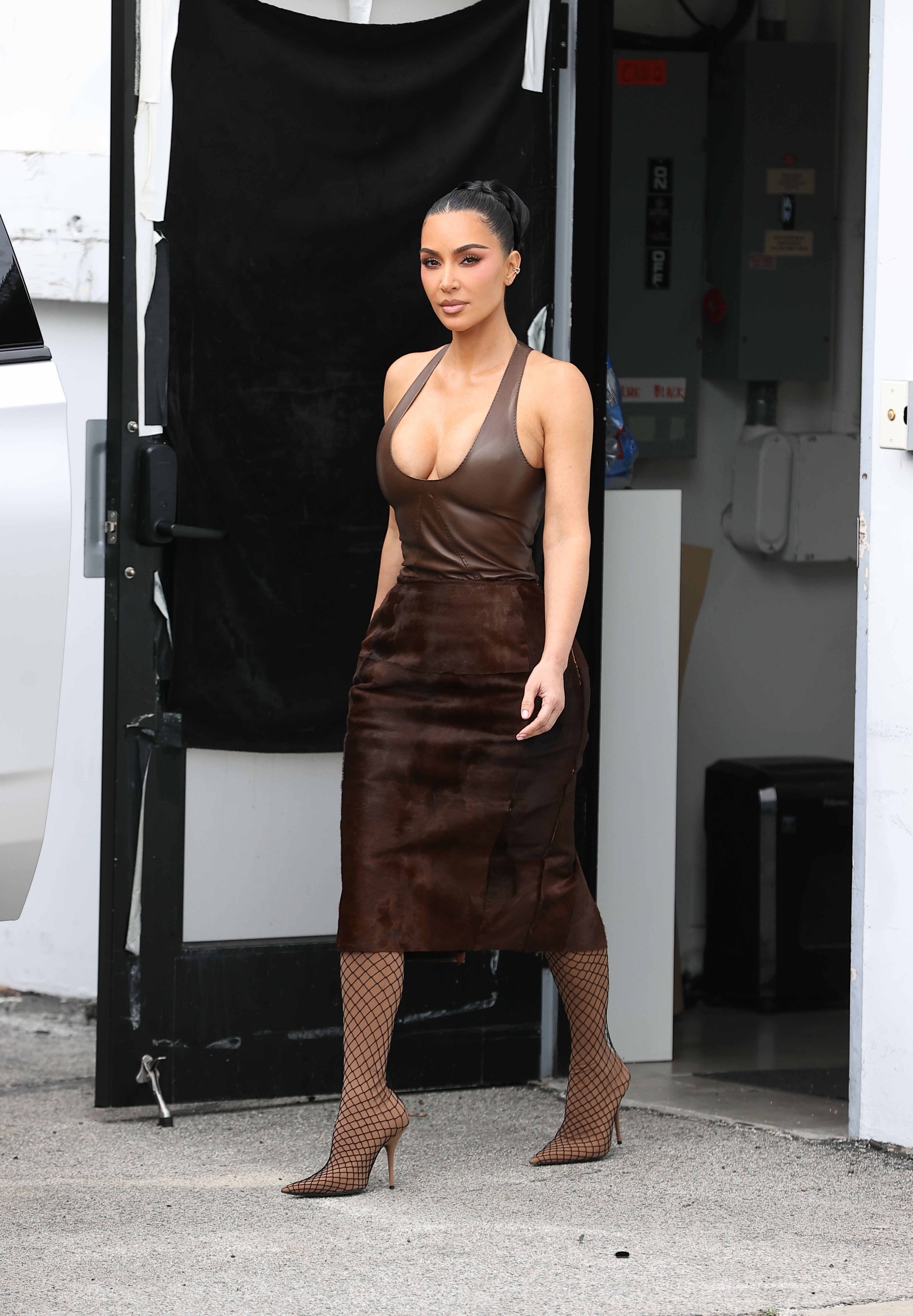 Kim Kardashian was spotted outside a L.A. photoshoot in a leather and ponyhair skirt set and fishnet boots