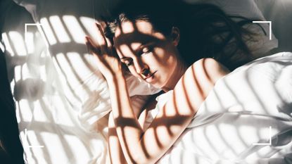 Woman asleep in bed with sunbeam coming through slats in the window, representing the positive sleep benefits of sleep divorce 