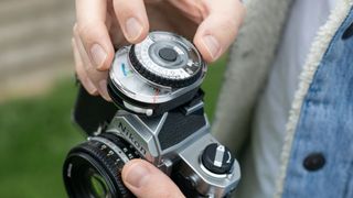 Man using Sekonic Twinmate L-208 light meter in the hot-shoe of a Nikon FM