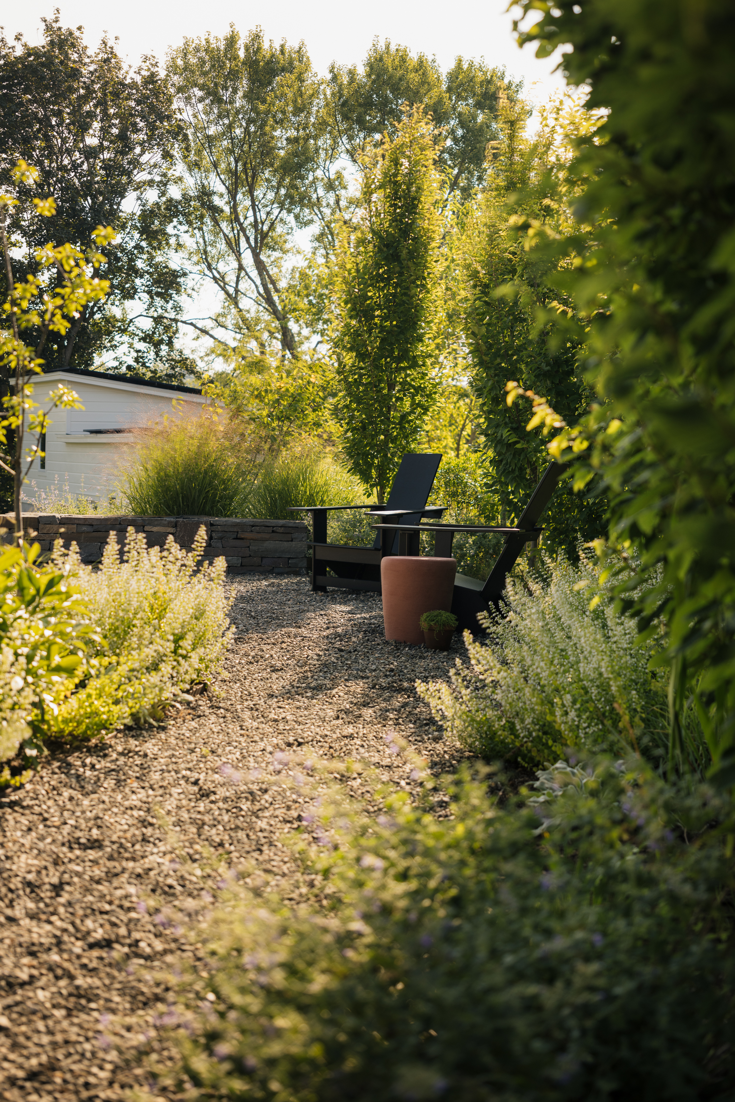 Gravelled patio with tall planting and two seats