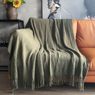 A dark green throw blanket on a leather sofa