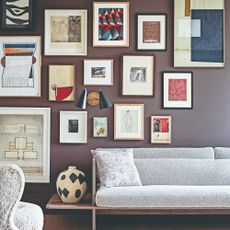 A purple-painted living room with a mixed gallery wall and wall lights