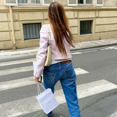 Eugénie Trochu walking across a street in Paris wearing an outfit ideas with the 2026 pink trend the French way, including a pink Courreges jacket.