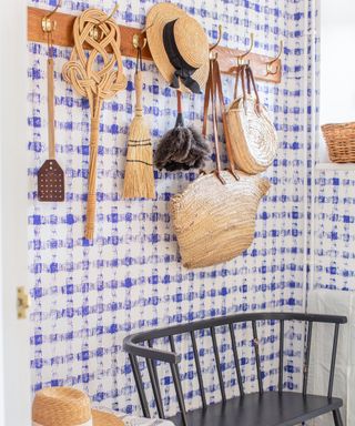 bootroom with a blue check wallpaper and peg rail with brushes hanging