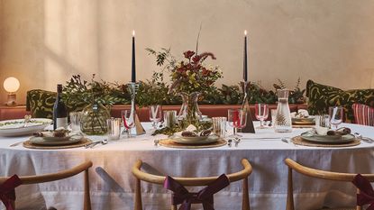 a table set for christmas with beautiful place settings, flowers, and candles