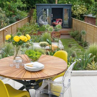 outdoor table in narrow garden with garden room at the end