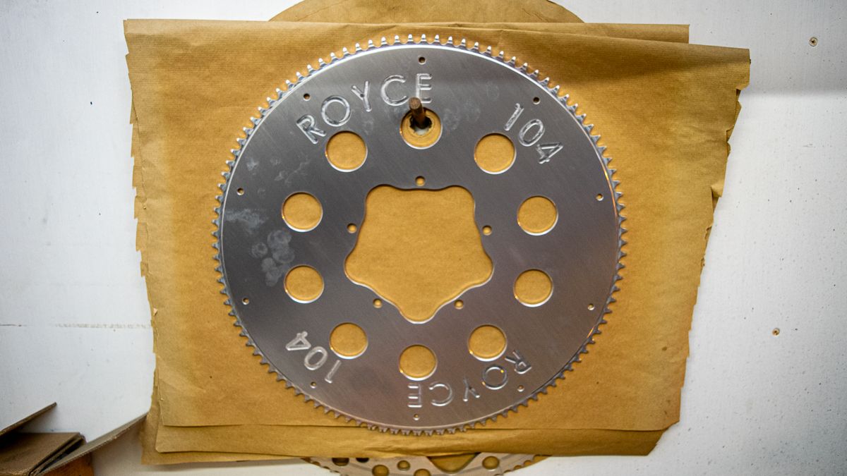 A 104 tooth silver Royce chainring hanging on a wall 