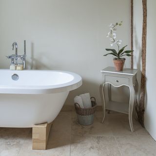 white freestanding bath in cottage bathroom with small grey painted side table