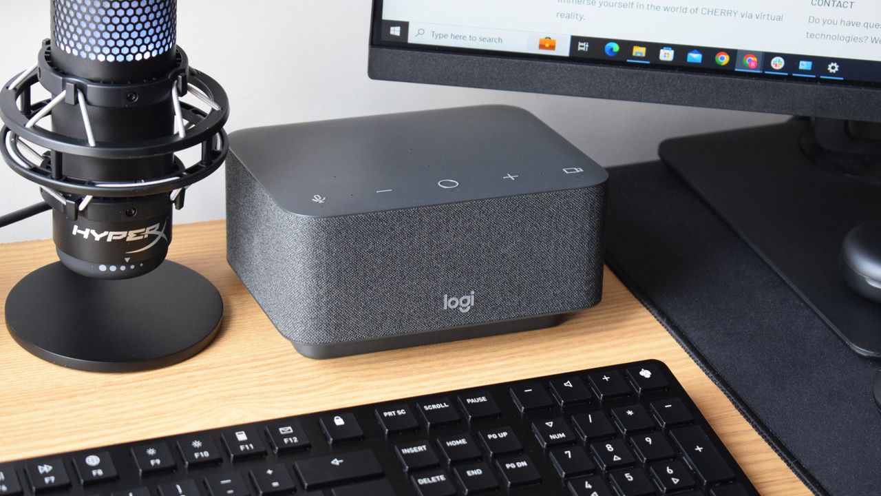 Photo of the Logitech Logi Dock docking station as part of a setup, powering a wired HyperX microphone, a CHERRY keyboard, and an external MSI monitor.