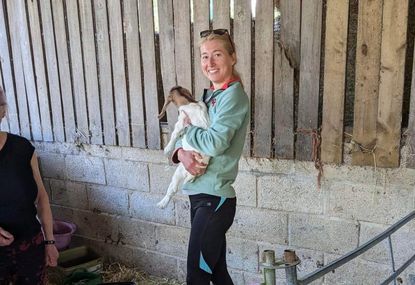 Phoebe Barker holding a goat on a farm