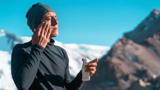 A skier applying sunscreen to his face