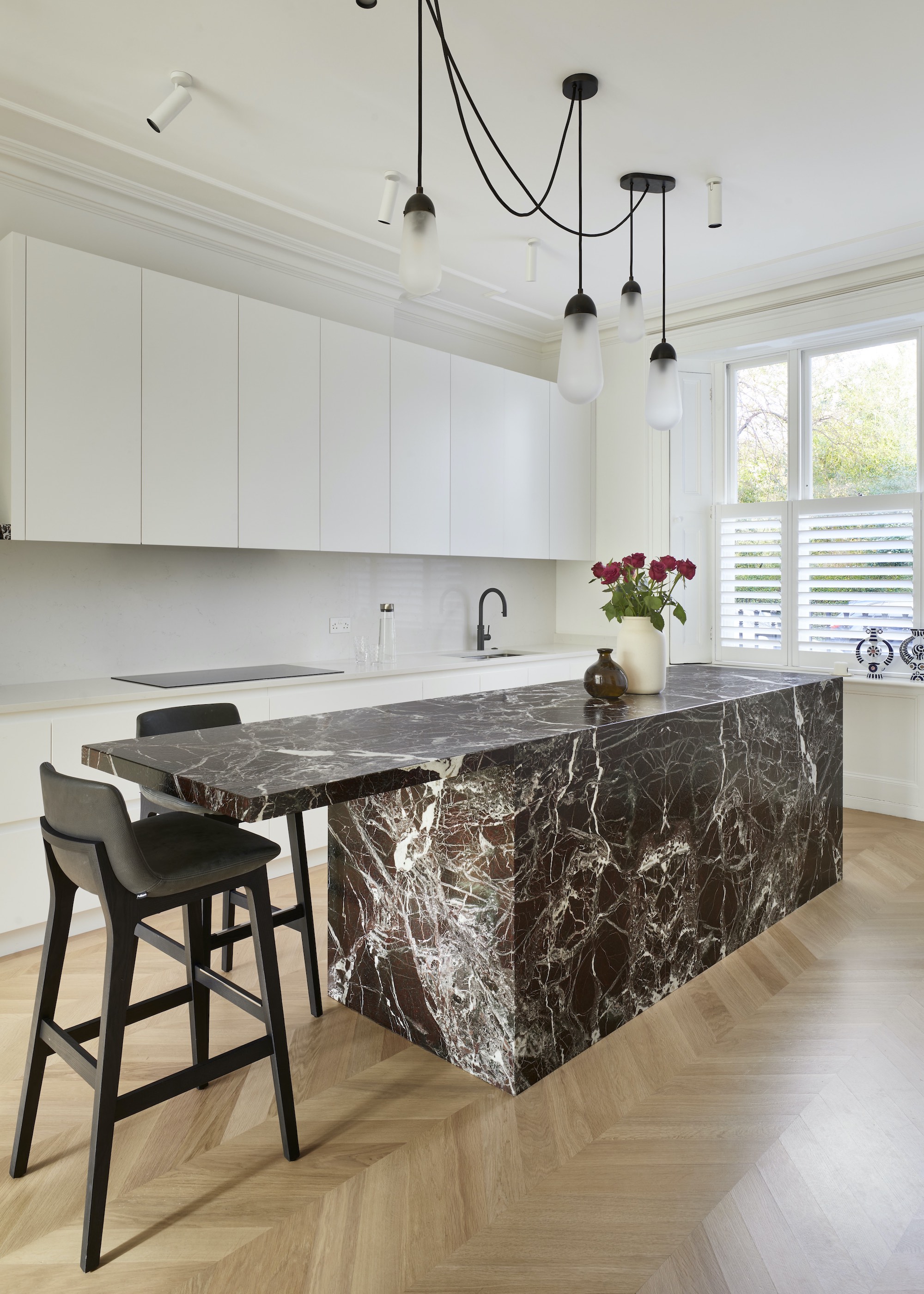marble island with black stone and black stools and white cabinets