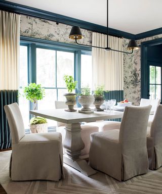 Blue dining room with dining table, cream dining chairs, plants on table, blue painted ceiling trim and paneling