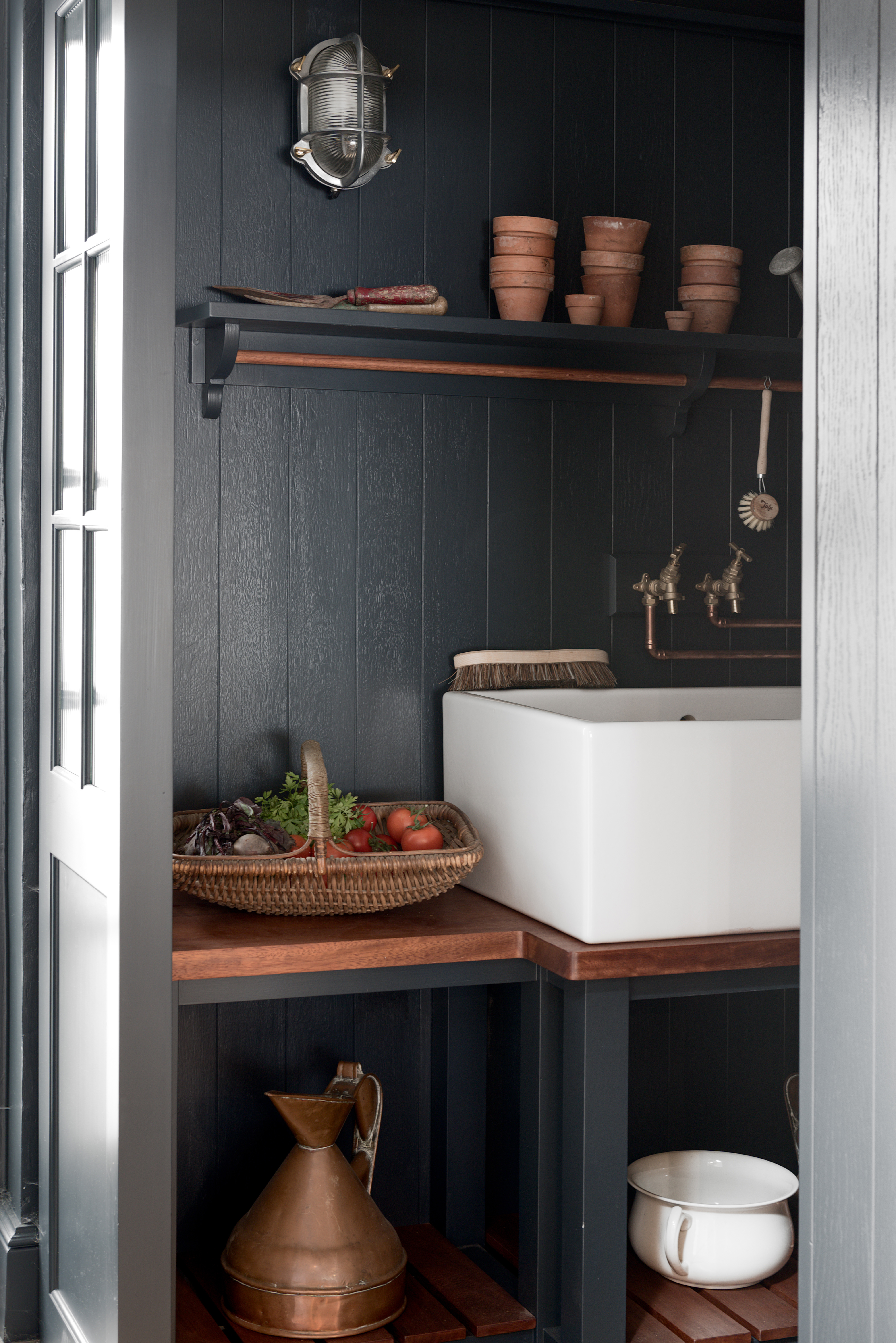 Small utility room ideas showing a dark room with stylish lighting and a basket of fresh vegetables