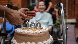 An elderly woman celebrates her 100th birthday with a cake. 