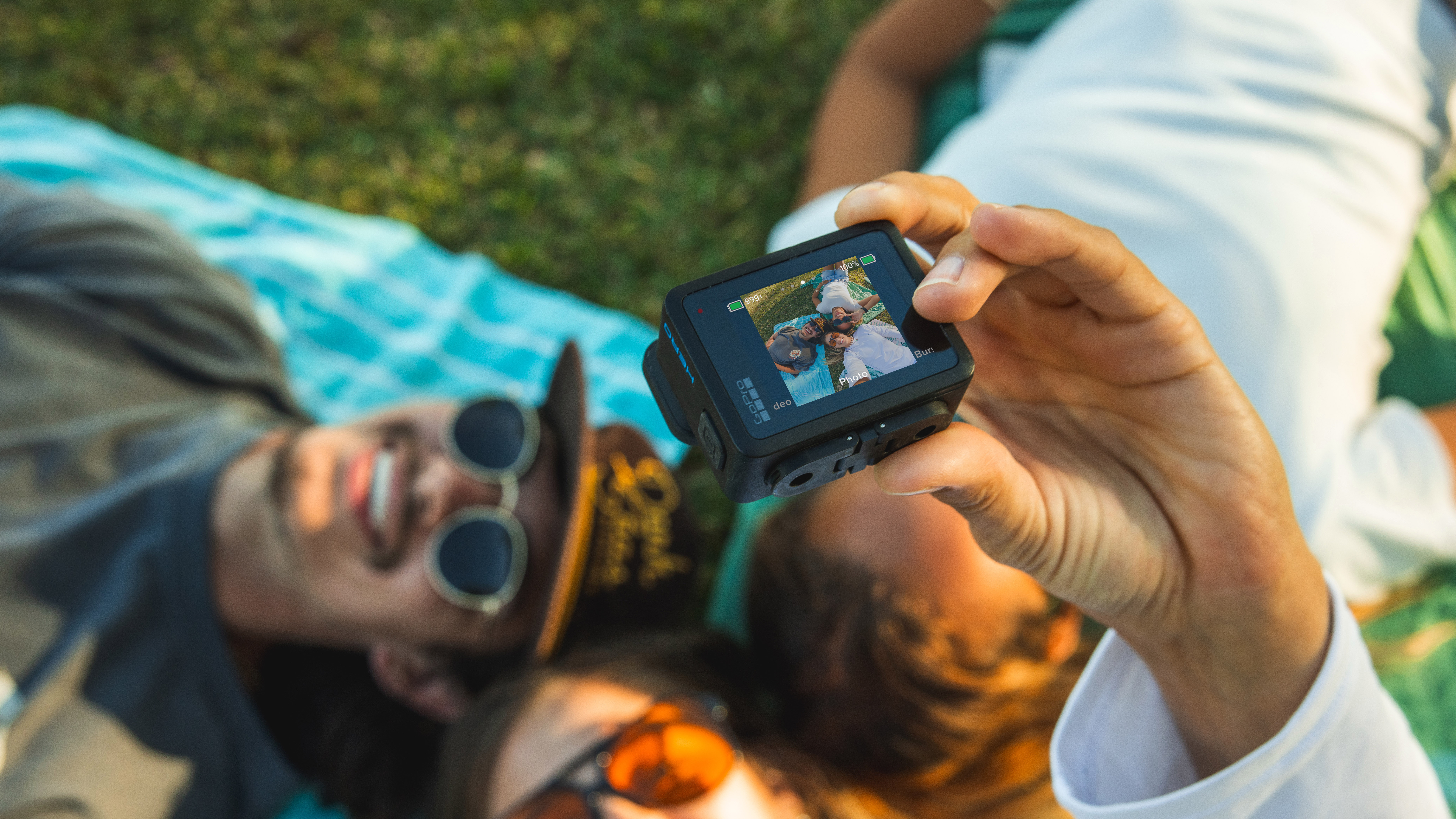 GoPro HERO action camera held up taking a photo of a group of people laying on the ground