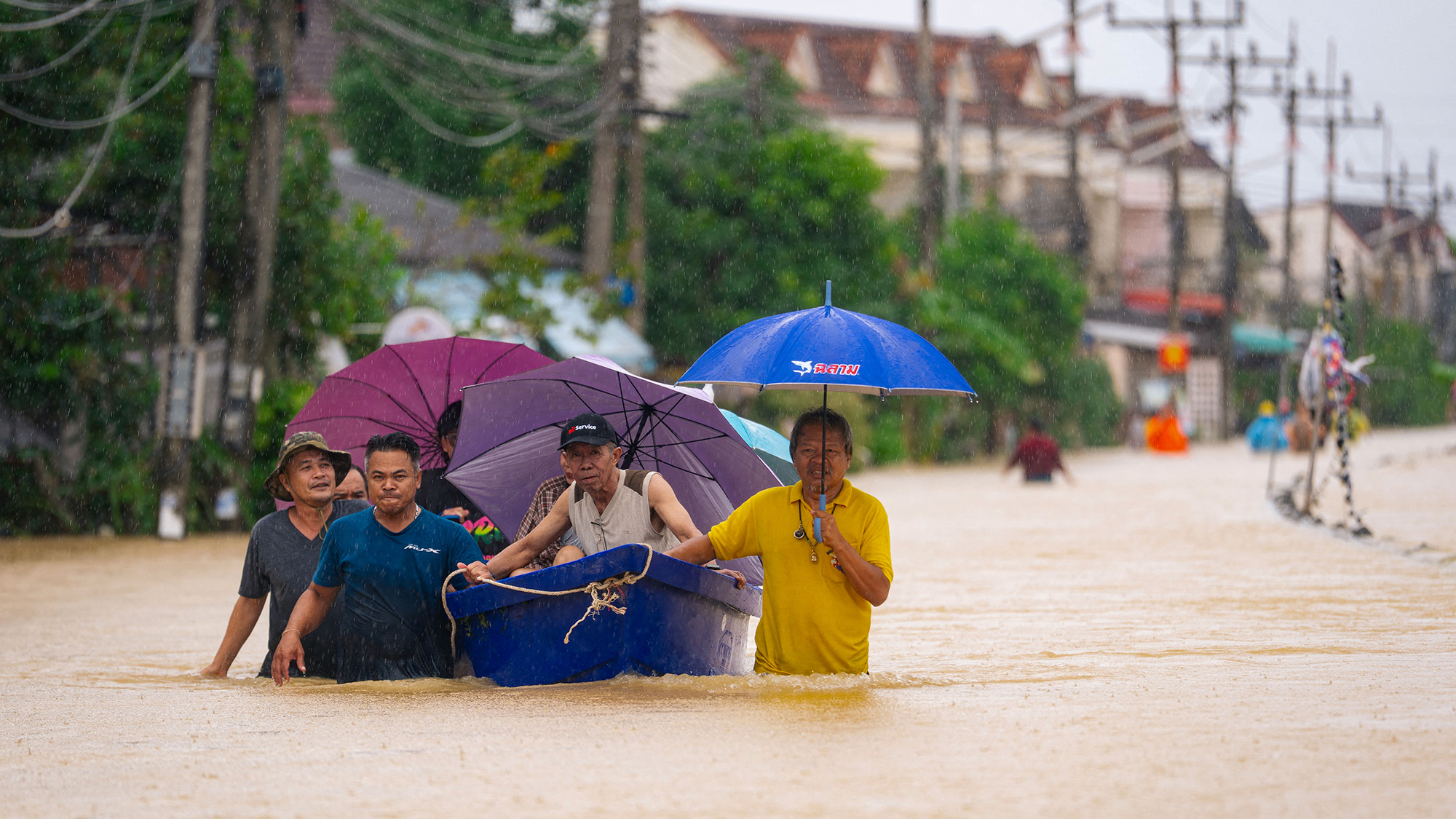 People wade through murky flood waters following severe flooding due to heavy rain in Hat Yai, Thailand