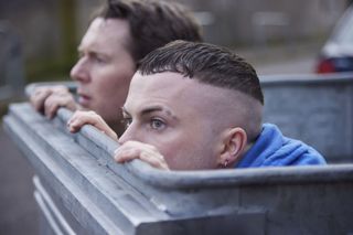 The Young Offenders season 4 stars Shane Casey and Alex Murphy in character as Billy and Conor hiding in a bin. 