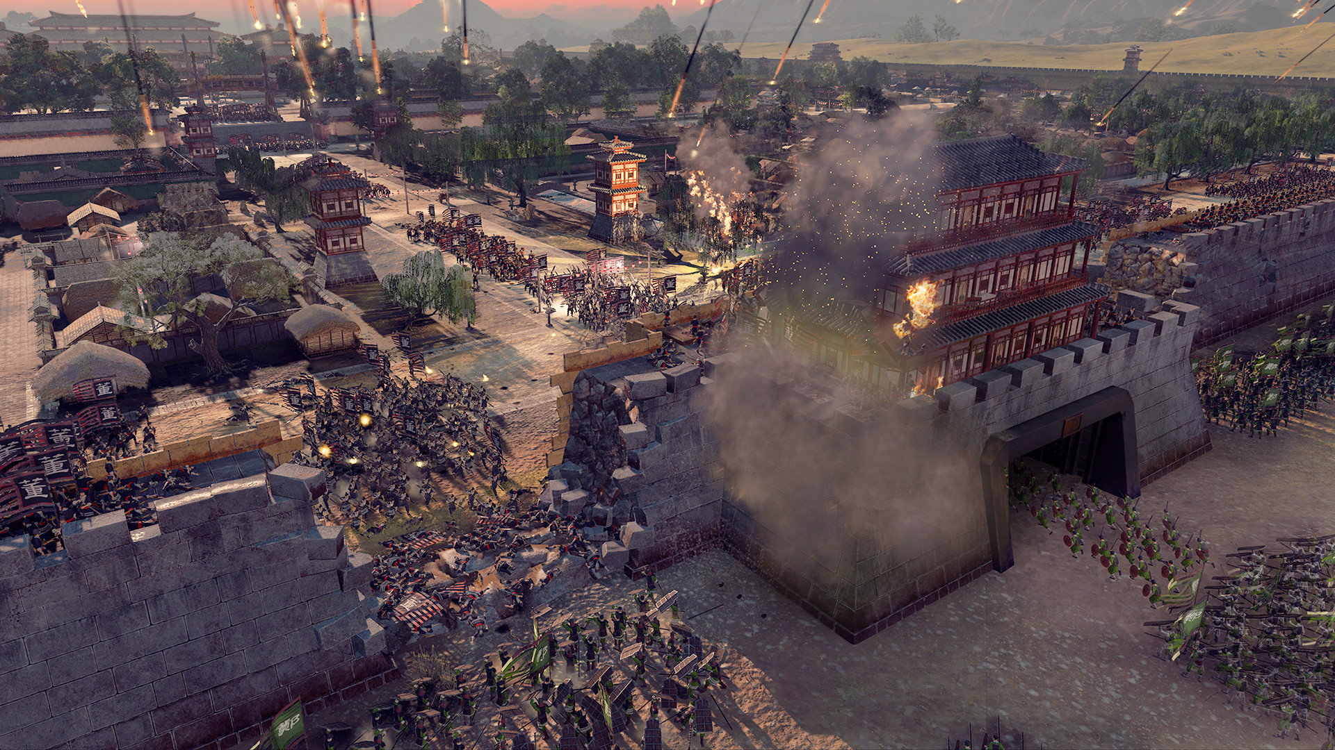 A gate to a city on fire with soldiers marching into the settlement during one of the best Total War games, Total War: Three Kingdoms