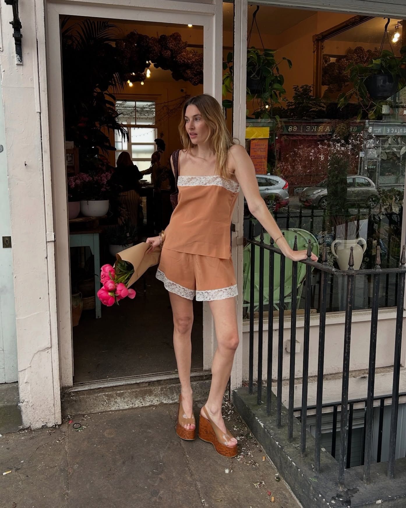 Influencer Camille Charriere wears a lace-trim short and cami set with wooden wedges.
