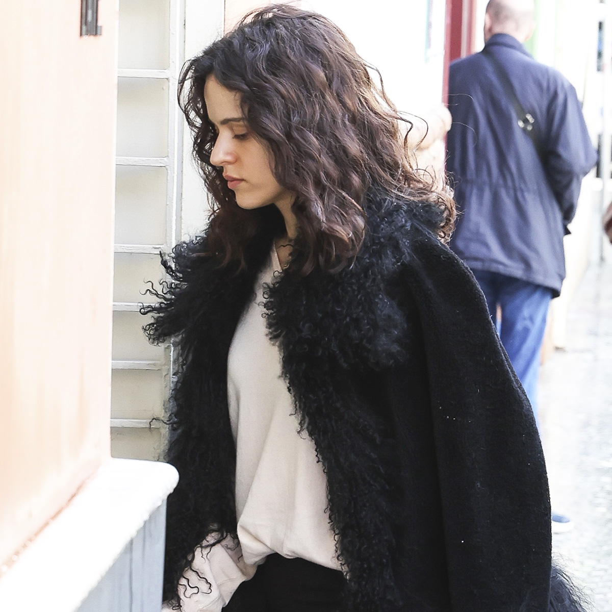 Rosalia wearing a fur-trimmed jacket with black capri pants and white ballet flats